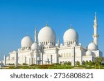 Sheikh Zayed Grand Mosque with multiple domes and minarets under clear blue sky in Abu Dhabi, United Arab Emirates. Islamic architectural heritage. Travel and tourism in UAE