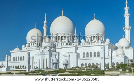 Sheikh Zayed Grand Mosque timelapse in Abu Dhabi, the capital city of United Arab Emirates. Back side with trees and traffic on the road. Blue sky at sunny day