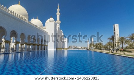 Sheikh Zayed Grand Mosque timelapse hyperlapse in Abu Dhabi, the capital city of United Arab Emirates. Side view with reflection in water pool. Blue sky at sunny day