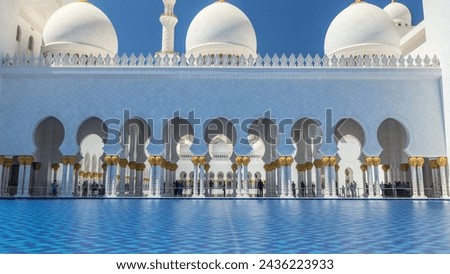 Sheikh Zayed Grand Mosque timelapse in Abu Dhabi, the capital city of United Arab Emirates. Side view with reflection in water pool. Blue sky at sunny day