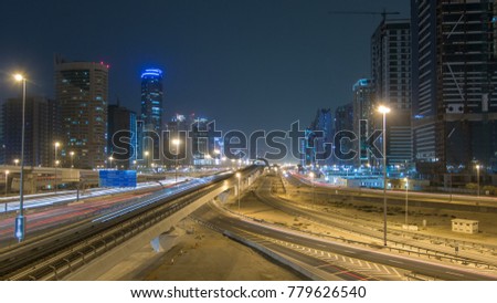 Sheikh Zayed road traffic night timelapse with Dubai marina and jlt skyscrapers. Line of Dubai Metro as world's longest fully automated metro network (75 km). Top view from bridge. Dubai, UAE