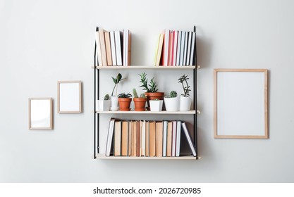 Shelf with books and plants hanging on light wall - Shutterstock ID 2026720985