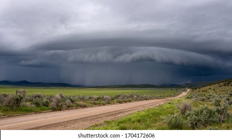 Shelf Cloud Storm Moving Over The Landscape With Road Leading Of Into The Distance Towards The Storm.