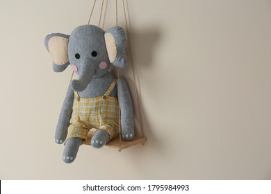 Shelf with cute toy elephant on beige wall, space for text. Child's room interior element