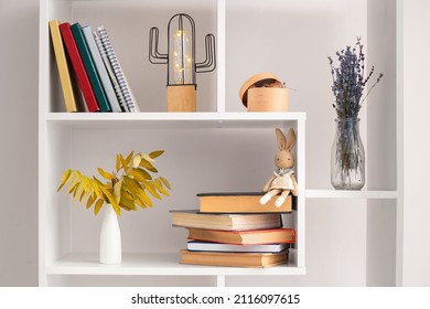 Shelf Unit With Different Books, Vases And Decor Near White Wall