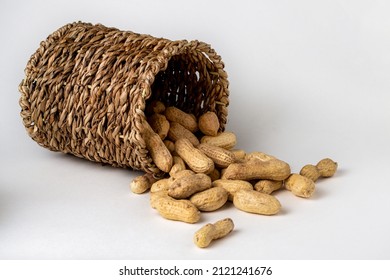 Shelled peanuts in a small wicker basket on a white background. Peanuts full from a wicker basket. Peanuts spill out of a wicker basket. photo
