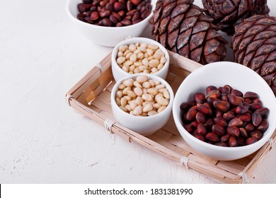 Shelled And Unshelled Pine Nuts And Pine Cones On The White Table