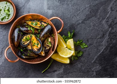 Shellfish Mussels in copper bowl with lemon and herbs. Shellfish seafood. Top view.