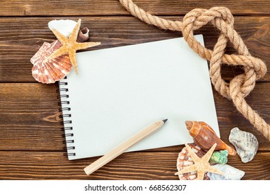 Shells and notepad on wooden table. Top view with copy space