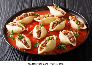 Shells pasta stuffed with ground beef with herbs in a marinara sauce close-up on a plate on a table. horizontal
