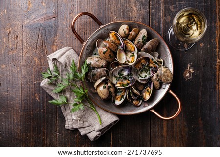 Shells vongole venus clams with parsley in copper cooking dish on dark wooden background 