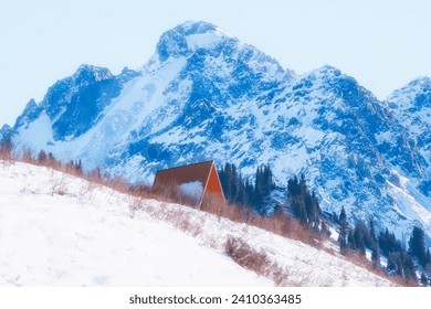 Shelter against the backdrop of harsh snowy mountain in winter. Nursultan Peak, former name Komsomol with glacier over mountain range in Almaty, Kazakhstan