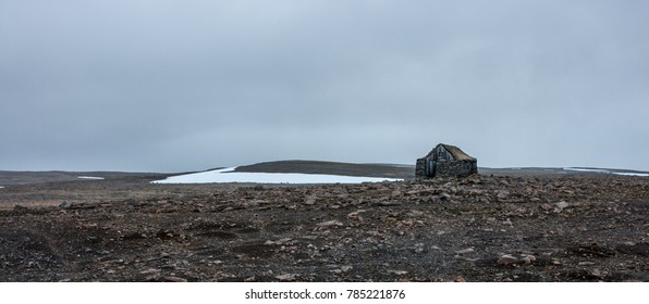 Shelter house build from rocks in a field of noman, rocky field with a snow stripe, wide angle - Shutterstock ID 785221876