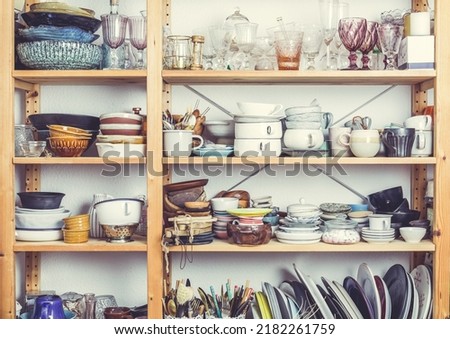 Shelves with kitchen clutter, utensils and kitchenware. Concept of tidying and decluttering