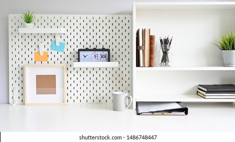 Shelves And Pegboard With Office Supply On Workspace Table.