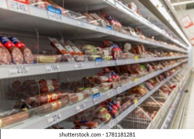 Shelves with sausage and smoked meat products in a large supermarket.  Big choice. Blurred.