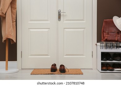 Shelving unit with shoes, coat rack and door mat in hall - Powered by Shutterstock