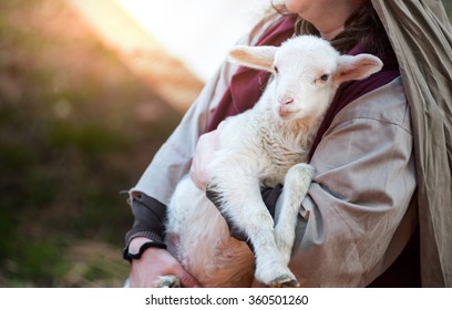 Shepherd holds the lamb in her arms.