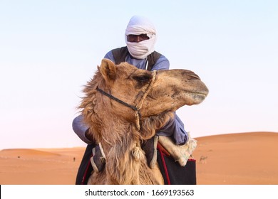  A Shepherd  Man Riding A Camel In The Desert. Front View Image