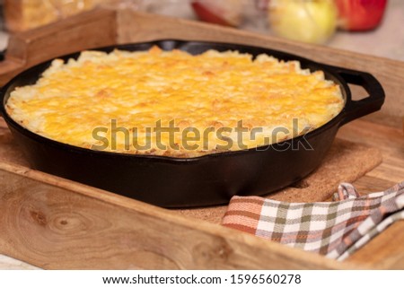 Shephers Pie baked in a cast iron skillet and placed on a wood tray with an apple and napkins