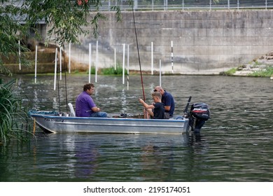 Shepperton, UK  August 28th 2022 Two Men And A Boy Fishing In A Small Boat On The River Thames Next To A Weir And Kayak Slalom Poles