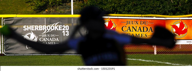 SHERBROOKE, CANADA - August 5: A Women's Softball Pitcher Is Silhouetted Against Canada Games Signage August 5, 2013 In Sherbrooke, Canada.