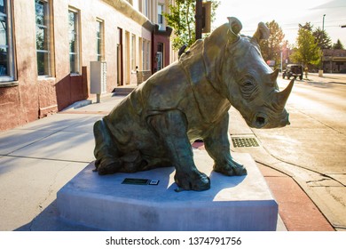 Sheridan, Wyoming - May 18 2017: Giant  Rhinoceros Statue Sitting On A Small Town Street Corner.  