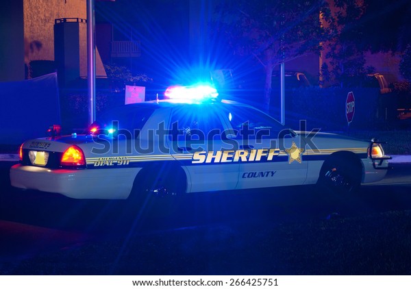 Sheriff cruiser car with his lights on at night on\
a call to protect the\
peace