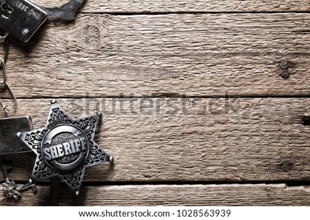 Sheriff star and handcuffs on wooden table closeup. Law concept background