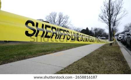 SHERIFFS YELLOW CAUTION TAPE ( sheriffs line do not cross), over a side walk ,tide from a tree 