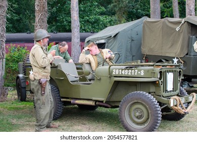 Sheringham, Norfolk, UK - SEPTEMBER 14 2019: Men In 1940s Army Wait By A 1941 Willys MB Military Jeep