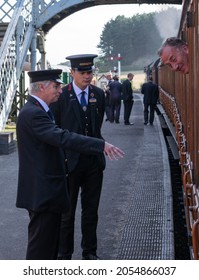 Sheringham, Norfolk, UK - SEPTEMBER 14 2019: Man And Teenager In 1940s Train Conductor Uniforms Speak To Man On A 1924 LNER Quad Art Set 48661-4 Vintage Passenger Carriage