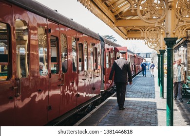 Sheringham, UK - April 21, 2019: Conductor in uniform walking past a retro Poppy Line steam train at Sheringham station. Sheringham is an English seaside town within the county of Norfolk, UK.