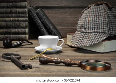 Sherlock Concept. Private Detective Tools On The Wood Table Background. Deerstalker Cap,  Magnifier, Key, Cup, Notebook, Smoking Pipe. Front View