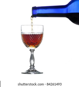 Sherry, Port Or Whisky Being Poured From Blue Wine Bottle Into An Elegant Cut Glass And Isolated Against White