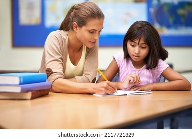 She's a dedicated educator. Shot of a teacher helping her student with her work in the classroom. - Powered by Shutterstock