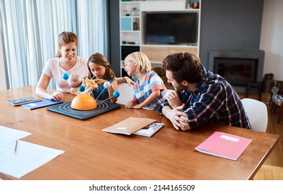 Shes Going To Take Over The World One Day. Shot Of A Beautiful Young Family Working Together On A Science Project At Home.