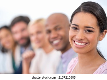 Shes Got Ambition. Portrait Of An Attractive Business Woman Smiling At The Camera With A Row Of Business People Behind Her.