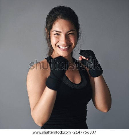 Shes got a lot of fight in her. Studio shot of a female kickboxer against a gray background.