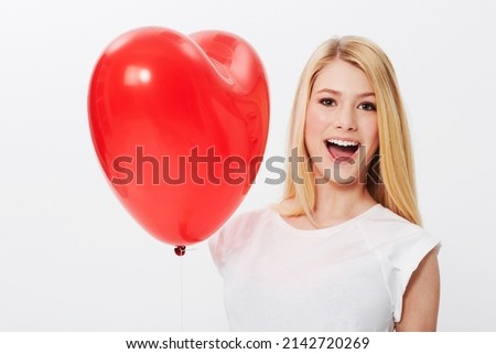 Shes got her heart on her sleeve. A gorgeous young blonde woman holding a heart while isolated on a white background.
