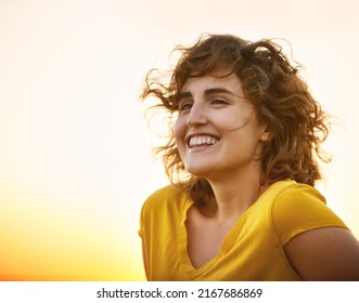 Shes Got Sunshine In Her Soul. Shot Of A Cheerful Young Woman Smiling While Standing Outside At Sunset.