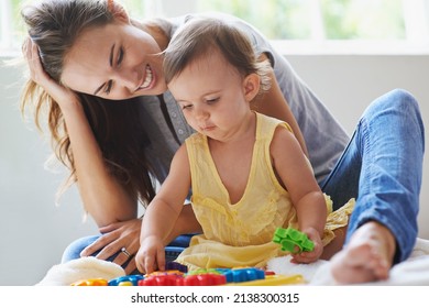 Shes A Little Genius Already. Shot Of A Cute Baby Girl Sitting On The Floor With Her Mom And Playing With Toys.