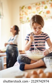 Shes Messy But A Natural. Shot Of A Little Girl Helping Her Mom Bake In The Kitchen.