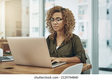 Shes One Detail Oriented Worker. Shot Of A Young Businesswoman Using A Laptop At Her Desk In A Modern Office.