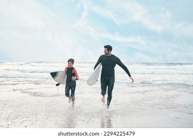 Shes ready to ride his own ripple. Shot of a man and his young son at the beach with their surfboards.