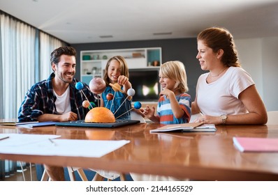 Shes Taking Us On A Journey Through The Galaxy. Shot Of A Beautiful Young Family Working Together On A Science Project At Home.