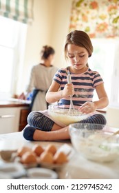 Shes a whiz with a whisk. Shot of a little girl helping her mom bake in the kitchen. - Shutterstock ID 2129745242