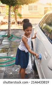 Shes So Young But Helpful. Shot Of A Young Girl Busy Cleaning A Car Outside.