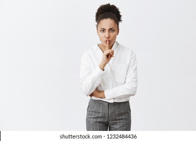 Shh Do Not Disturb, We Have Meeting Here. Annoyed Angry And Strict Female Entrepreneur In White Shirt And Pants, Frowning And Saying Shush, Holding Index Finger Over Mouth, Demanding Silence In Class