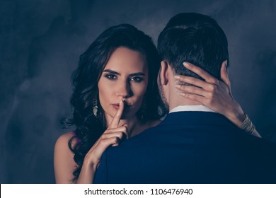 Shh! Portrait of tempting brunette lady showing silence sign with forefinger touching secret mysterious gentlemen with rear view, lovely Mr and Mrs isolated on grey background